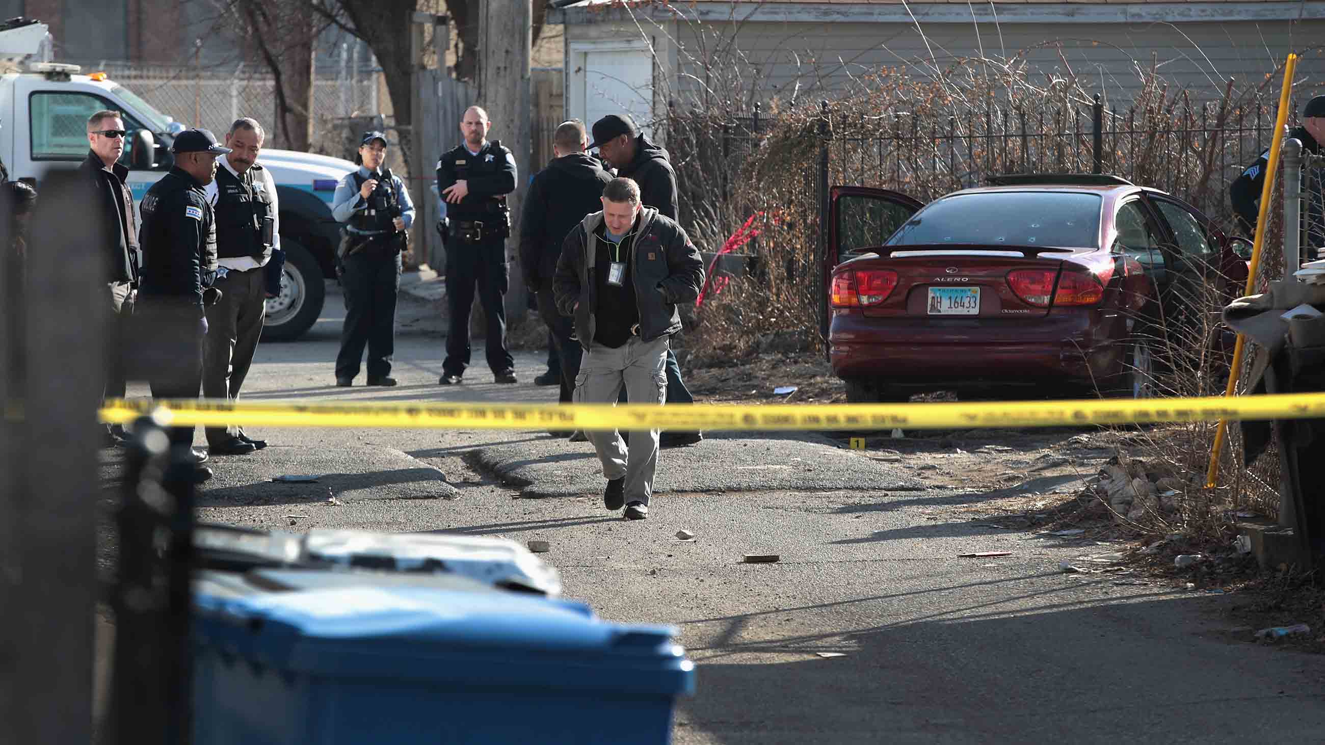 Police examine a bullet-riddled car after gunmen opened fire, killing a two-year-old child and his uncle in the Lawndale neighborhood of Chicago in February.