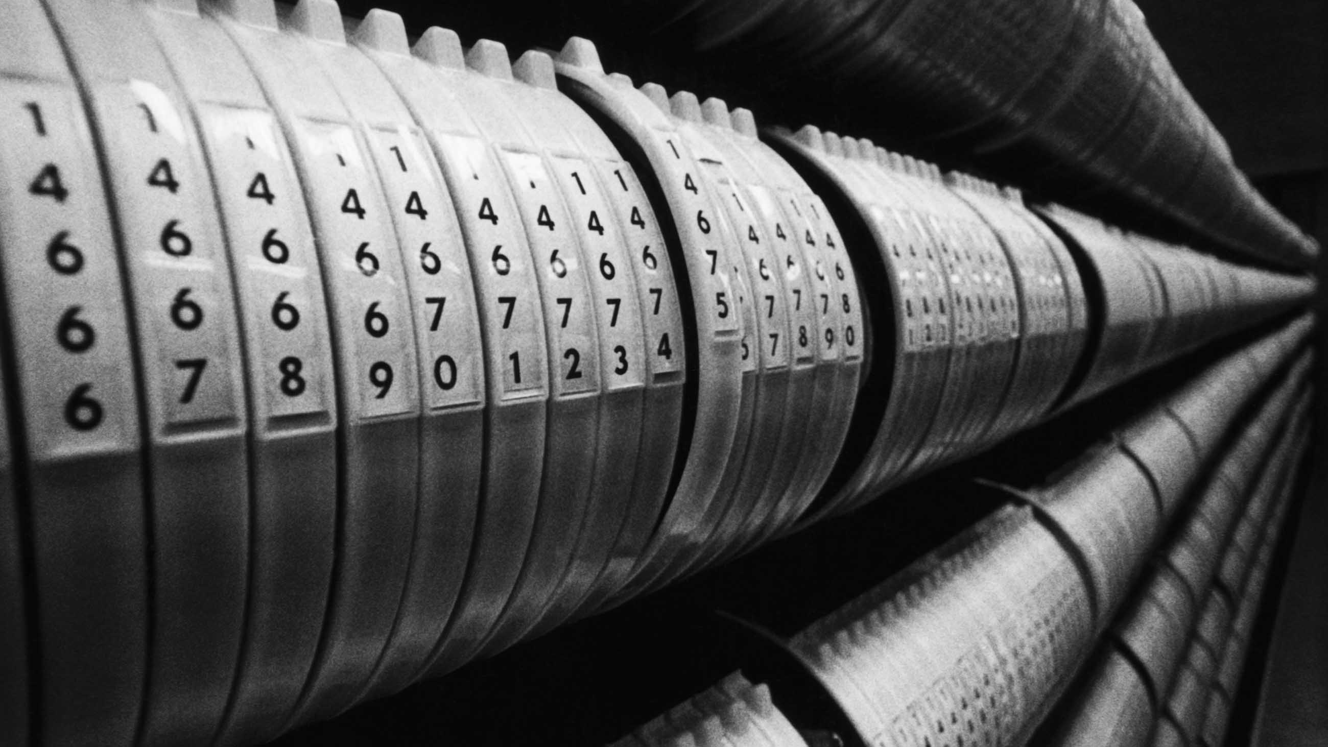 Photograph displaying long, numbered rolls of computer tape used in early computers. Undated photograph.