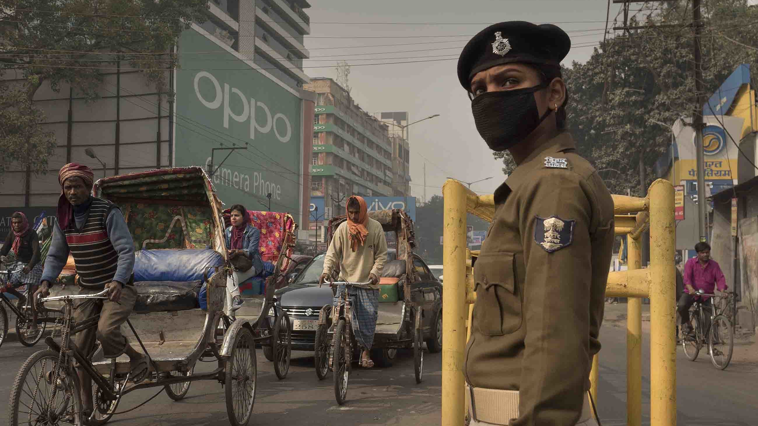 Traffic policewoman Sandhya Bhartj directs traffic in central Patna. Her  cloth mask does little to protect her from the smallest particulate pollution.