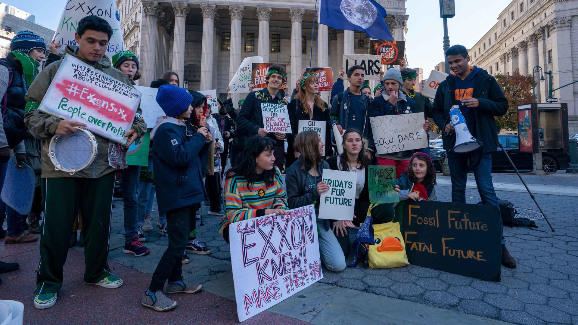 Climate protesters gather across the street from the New York County Courthouse, where a judge ruled in favor of Exxon Mobil this week.