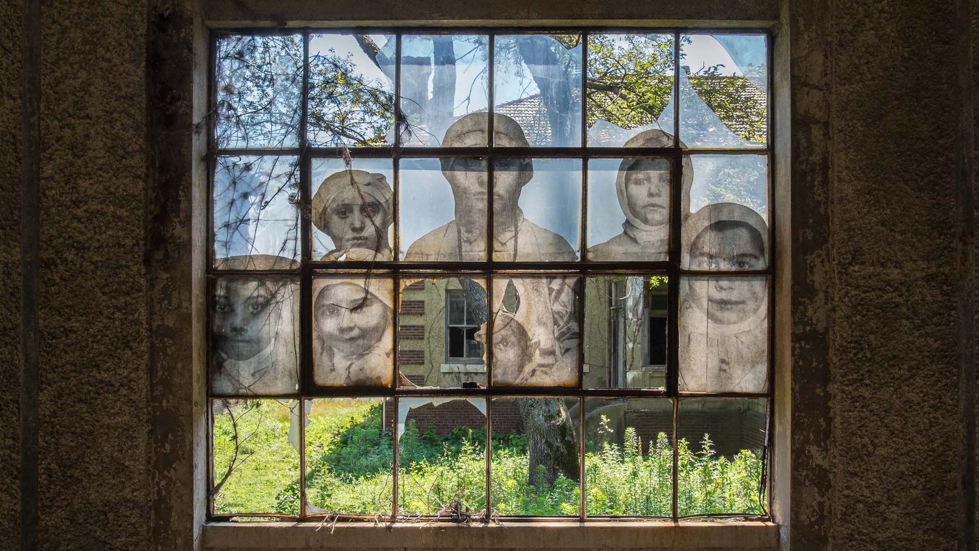A window in the Ellis Island Immigrant Hospital, closed since 1930, displaying an early 20th century photograph.