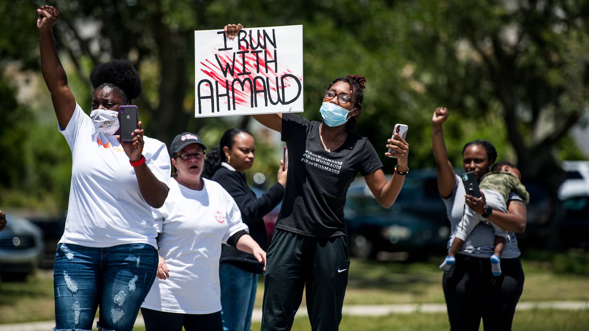 Demonstrators raise their fists at a parade of passing motorcyclists riding in honor of Ahmaud Arbery at Sidney Lanier Park on May 9, 2020 in Brunswick, Georgia.