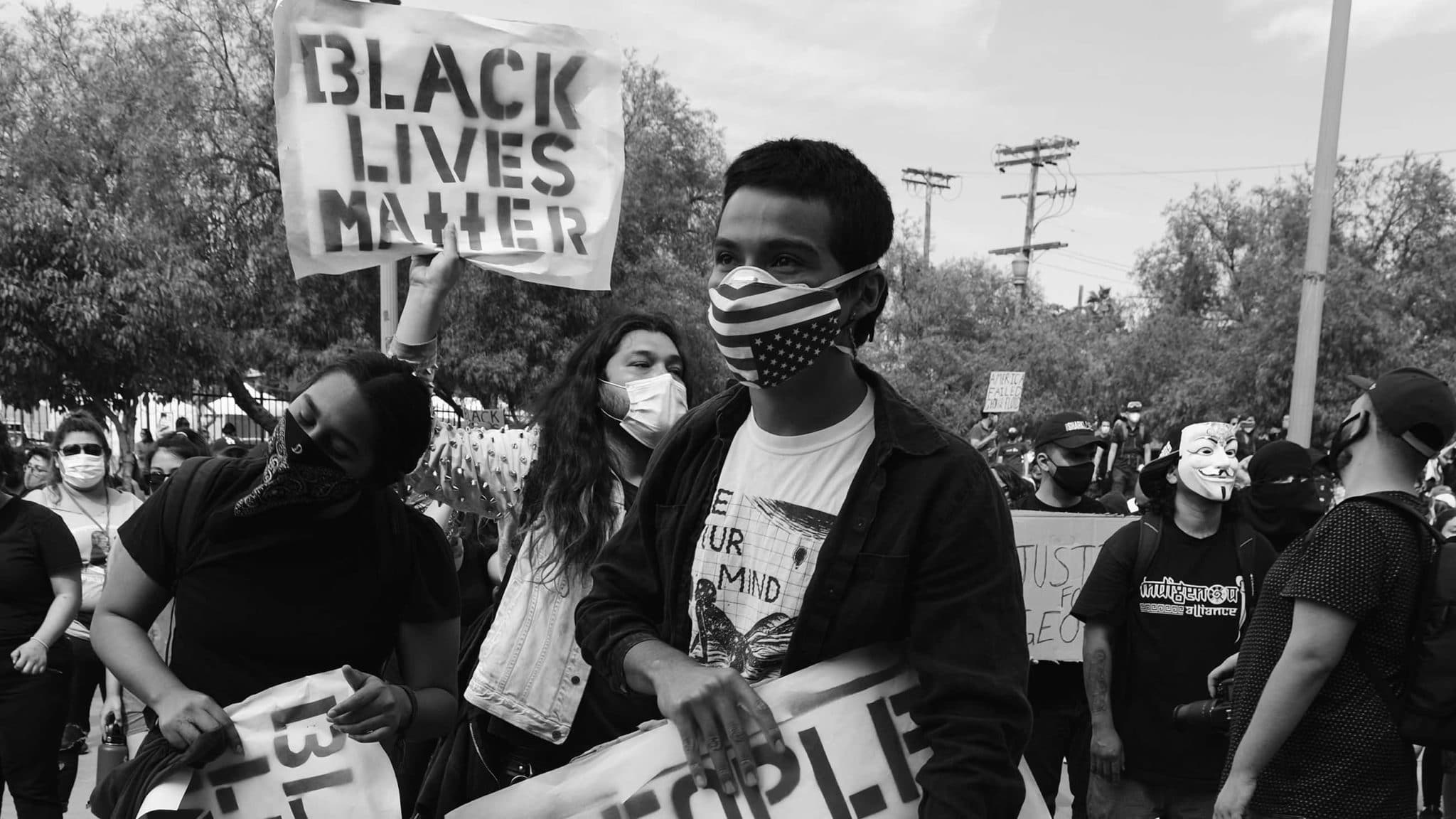 A group of Black Lives Matter protesters holding signs and wearing masks to protect from Covid-19.