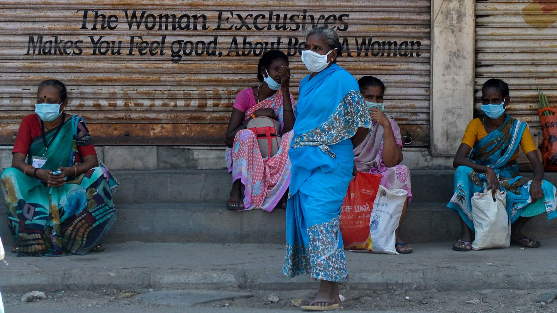 Women wearing facemasks sit in front of closed shops in Chennai during India's nationwide lockdown in April 2020.