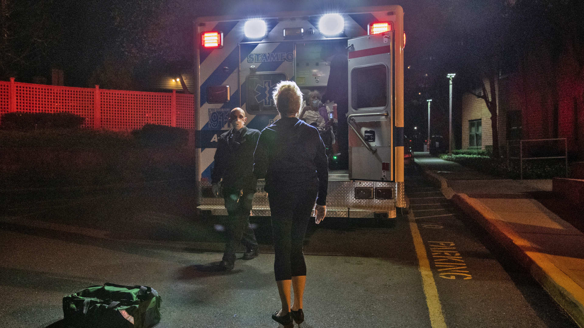 A woman in Connecticut watches as EMTs taker her mother to the hospital in April 2020. Due to the pandemic, she was not allowed to accompany her mother or visit her while in the hospital.