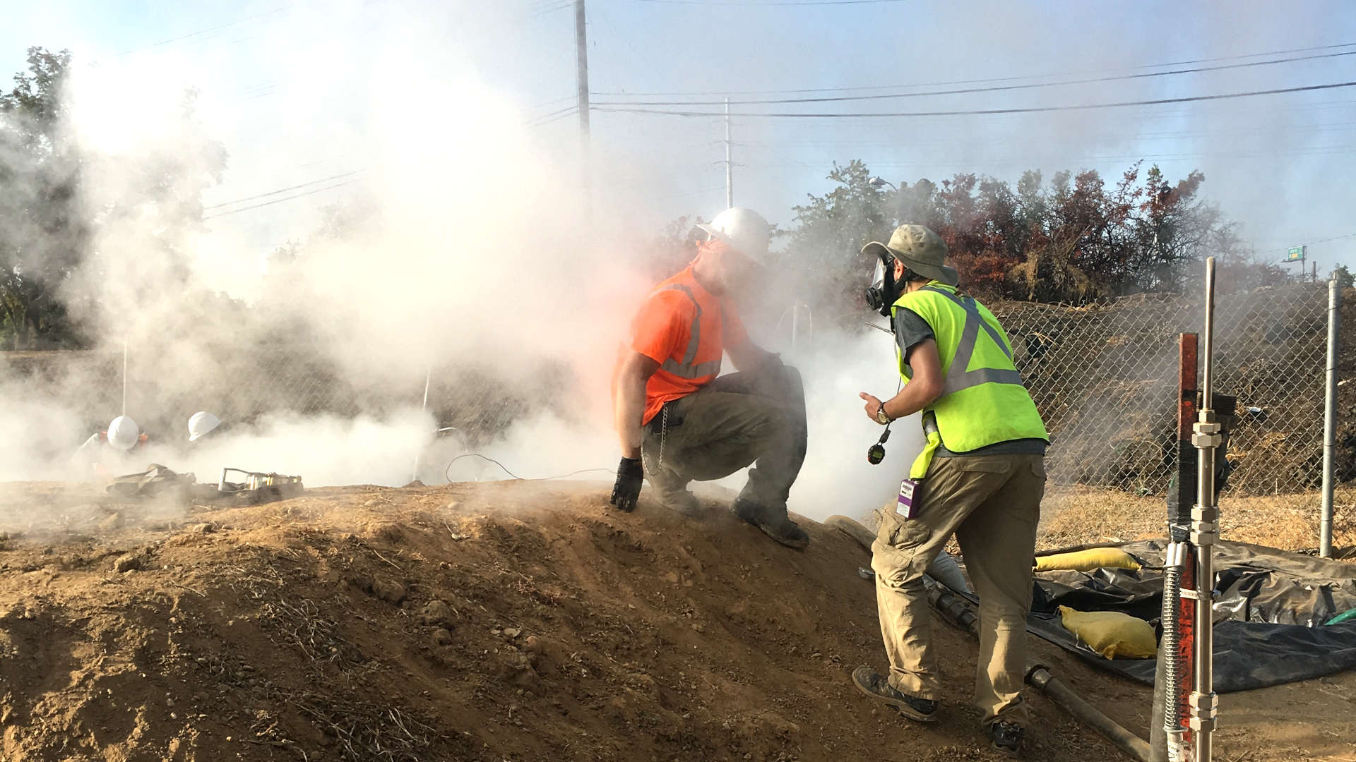 A worker, engulfed inside a plume created by the CIPP process, speaks with a researcher who wears a full face respirator to protect against chemical exposures.