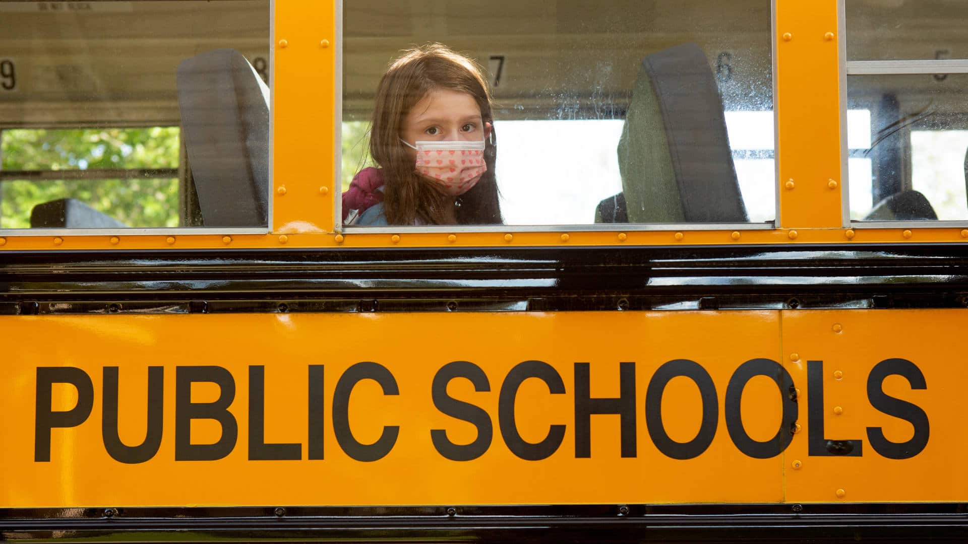 An elementary student waits for her bus to leave school.