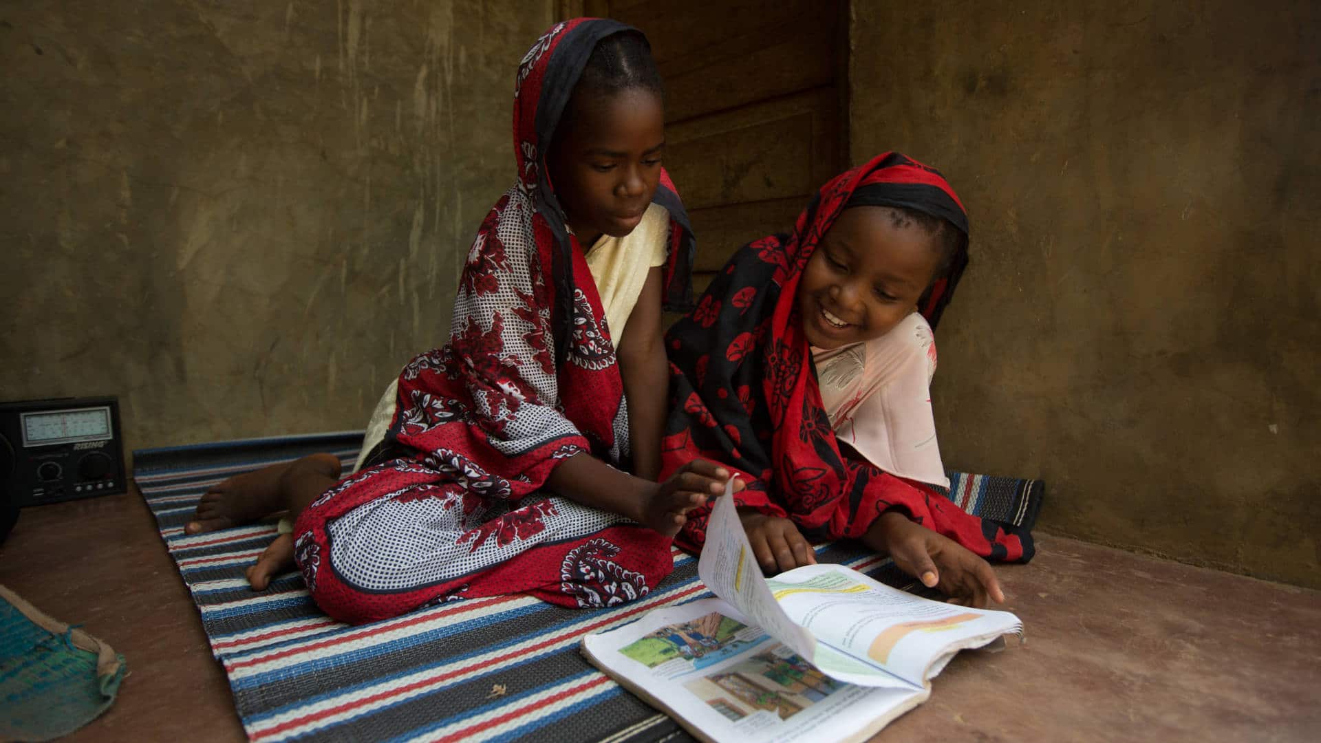 In Zanzibar, Tanzania, two girls study educational materials about preventing malaria — one of several diseases predicted get worse as suitable climate conditions for pathogens spread.