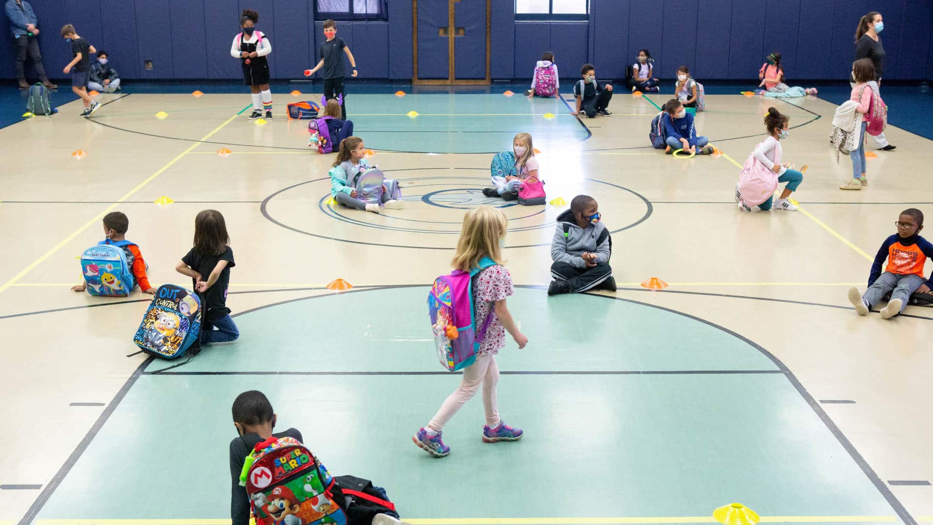 Elementary school students wait in the school gym for their rides home.
