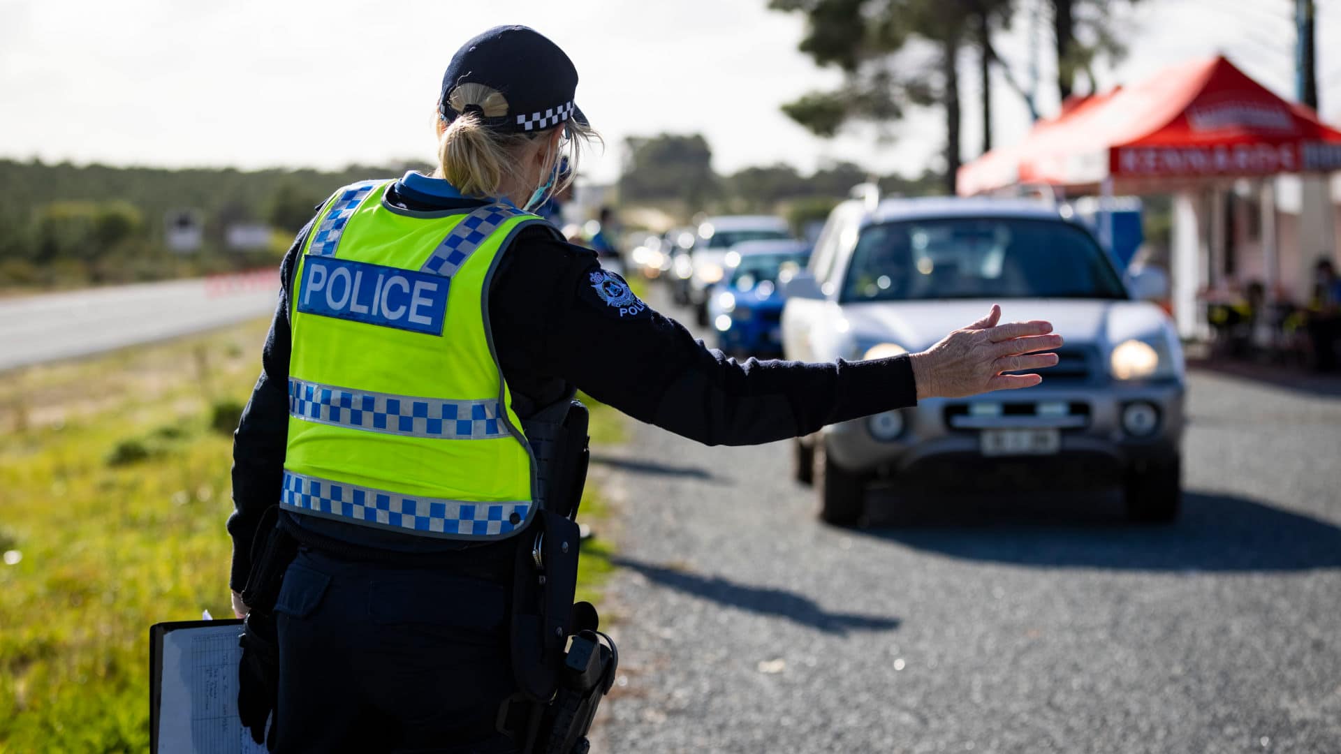 A member of the police force inspects cars at a border check point north of Perth, Western Australia on June 29, 2021. Due to the state's strict lockdowns and border closures, residents now go about their daily lives without the threat of Covid-19.