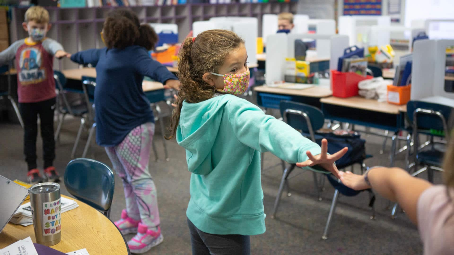 Second-grade students create distance between each other using their arms as they line up to go outside.