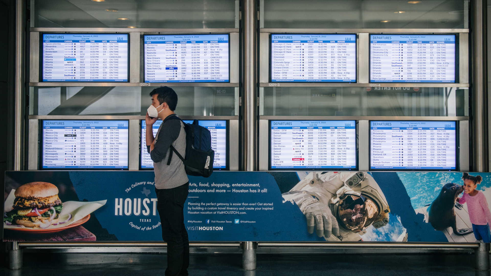 A person speaks on the phone near flight monitors at George Bush Intercontinental Airport in January 2022 in Houston, Texas.