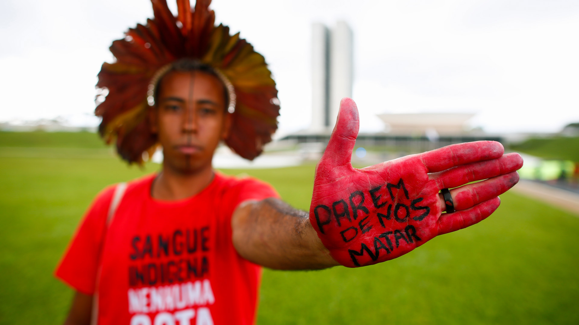 An Indigenous man's hand reads "Stop killing us" during a Feb. 2020 protest against a bill that would open Indigenous lands to mining in Brazil.