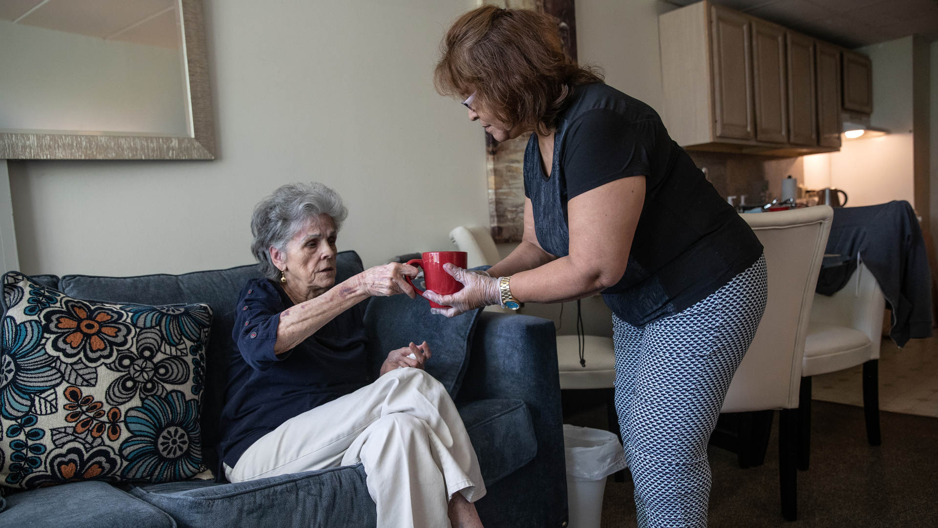 Janet Gazo, 89, receives tea from her home health care worker while continuing to fully recover from Covid-19 at home in May 2020.