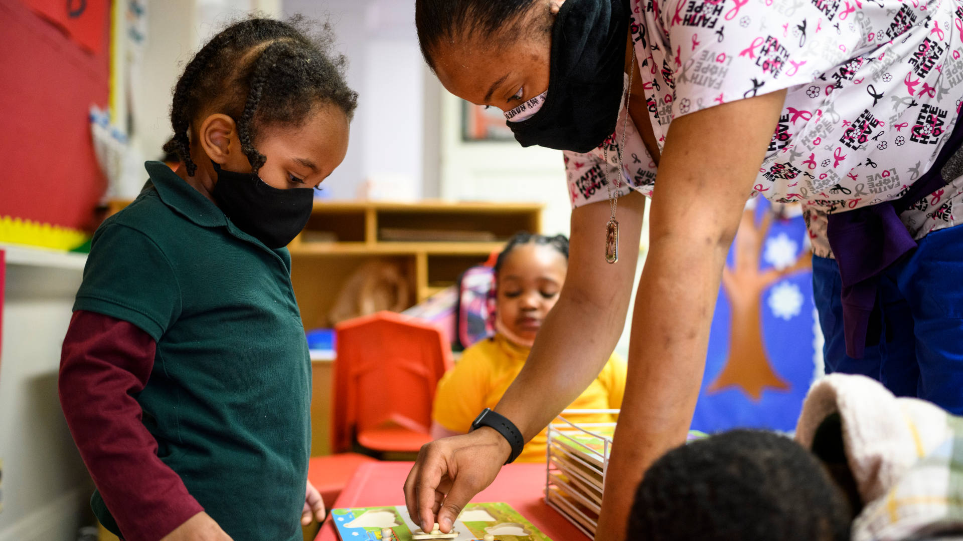 Shanikia Johnson, a teacher at  Little Flowers Early Childhood and Development Center in Baltimore, Maryland, helps one of her three-year-old students.