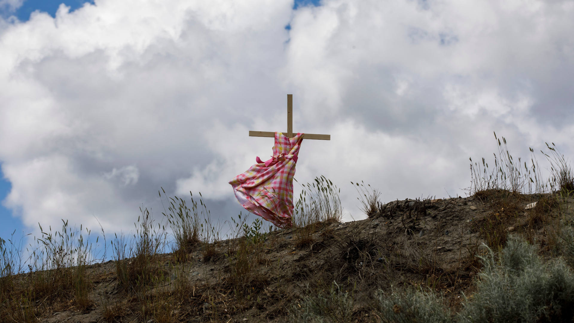 A staked child's dress blows in the wind on Highway 5 in June 2021, near the former Kamloops Indian Residential School where signs of unmarked children's graves have been found.