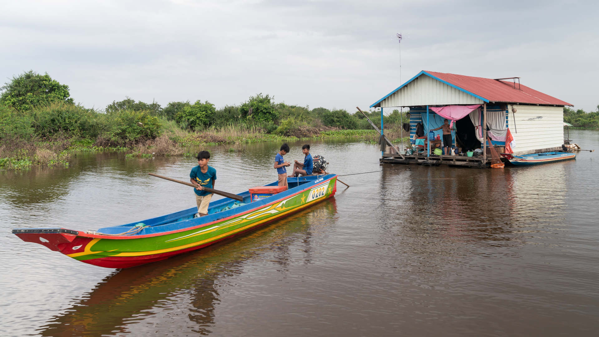 A family pulls their house farther out toward the Tonle Sap Lake as water levels remain abnormally low during rainy season 2019.