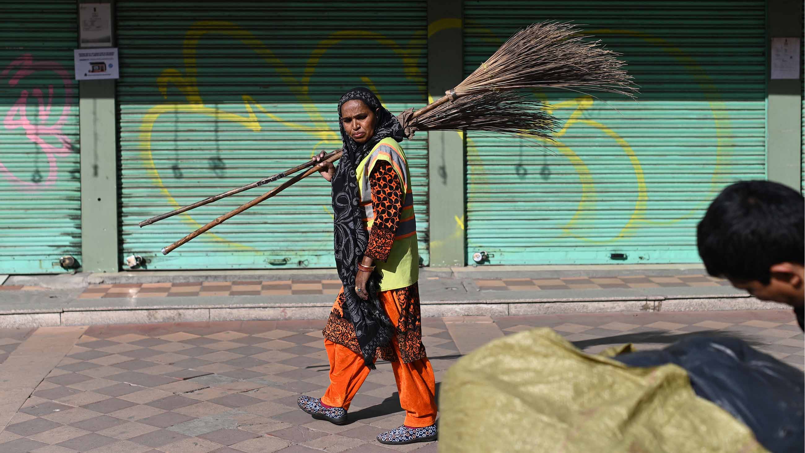 A street sweeper walks on a sidewalk in New Delhi on February 21, 2022.