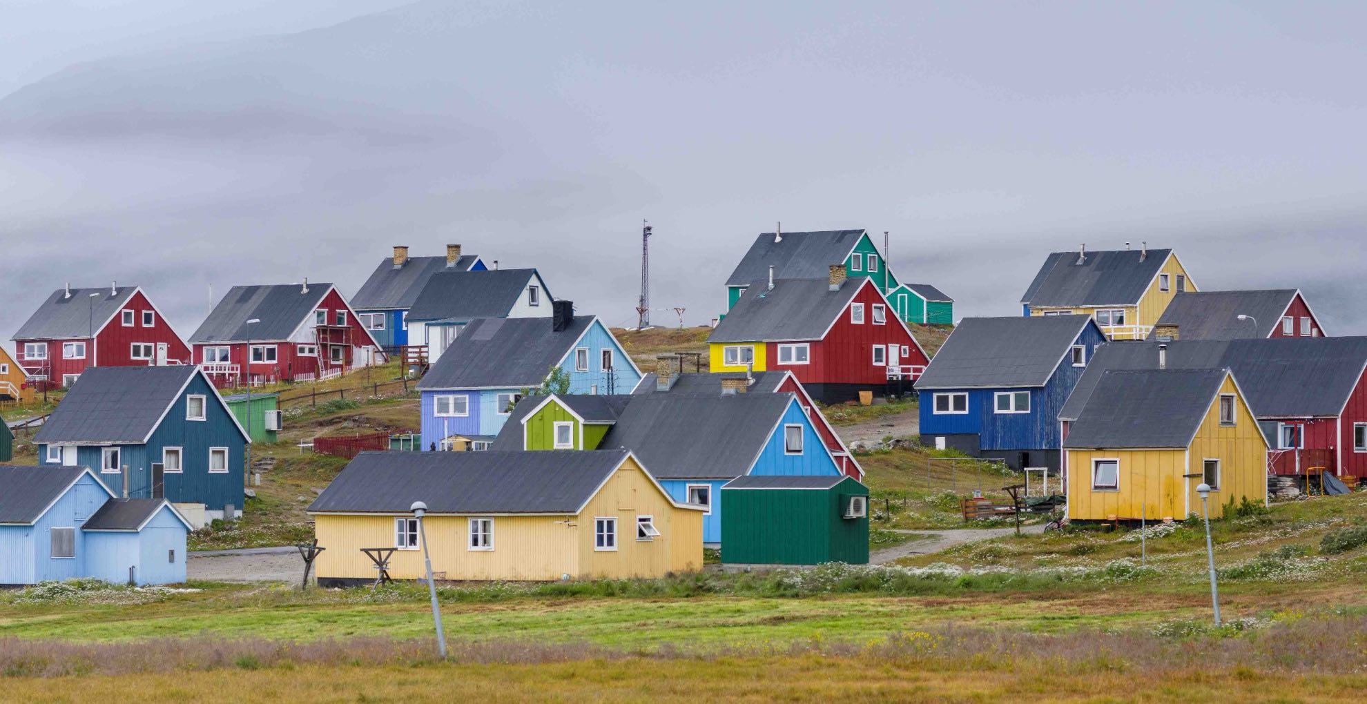Colorful houses dot the foggy hillside in Narsaq, Greenland.