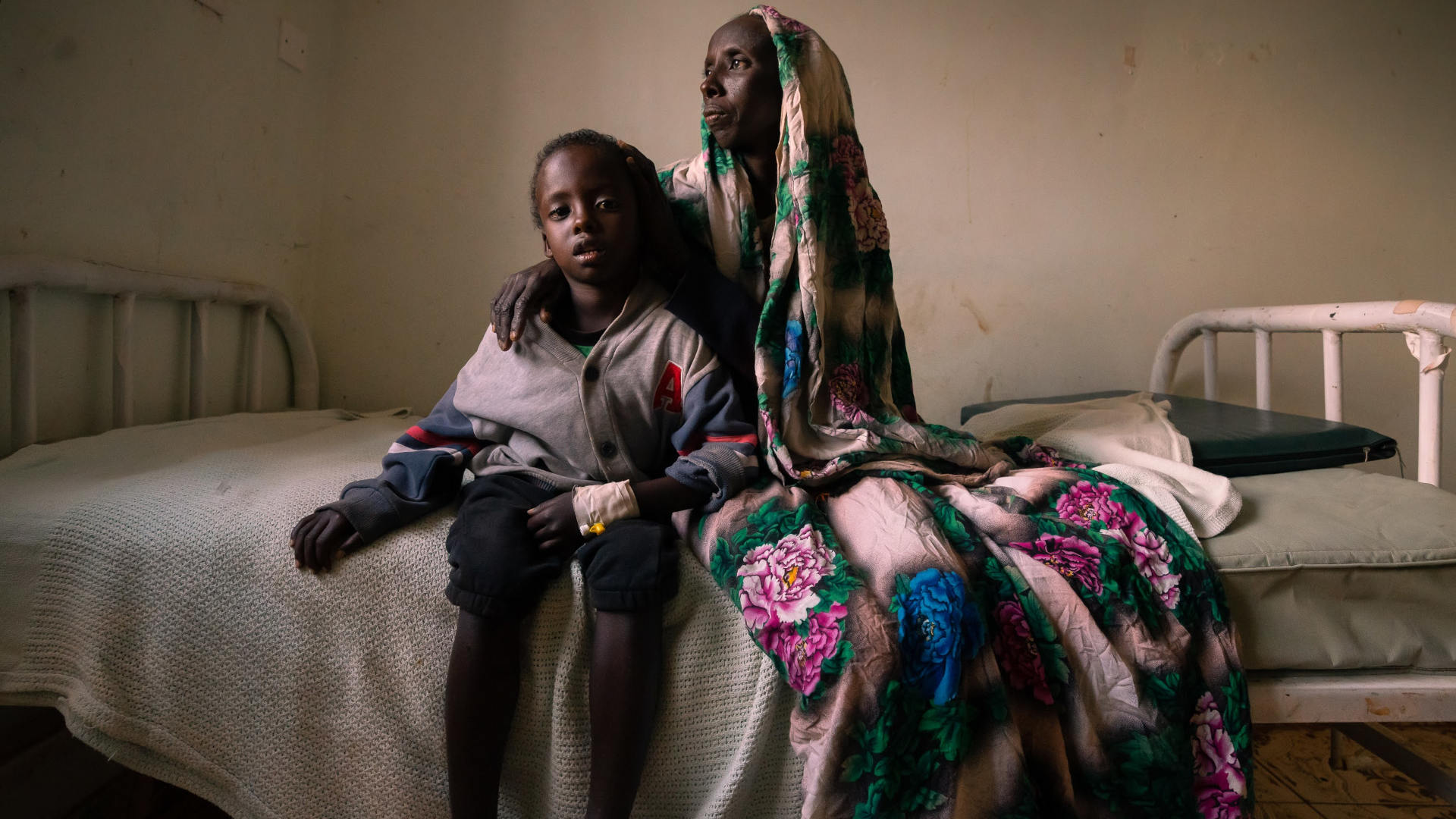 Ibrae Guyo, 7, sits on a bed at Marsabit County Referral Hospital with his mother, Salo Guyo. Ibrae was admitted with anemia, malaria, brucellosis, and malnutrition.