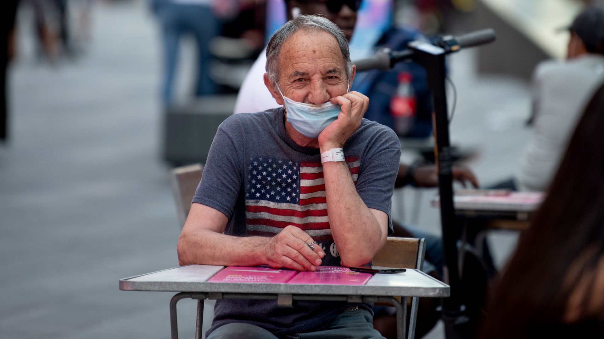 A man wearing a mask below his nose sits at an outdoor table in Times Square, New York City, in August 2020.