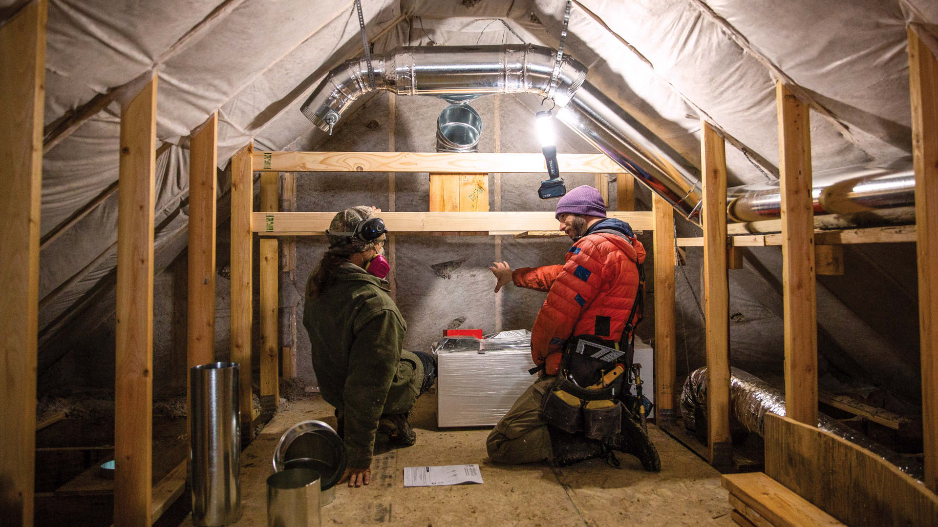 Cillian Liam Barrett and Edward Morrison install a heat pump system in the attic of a new accessory dwelling unit in Crested Butte, Colorado. The town recently passed new energy-efficient building codes.