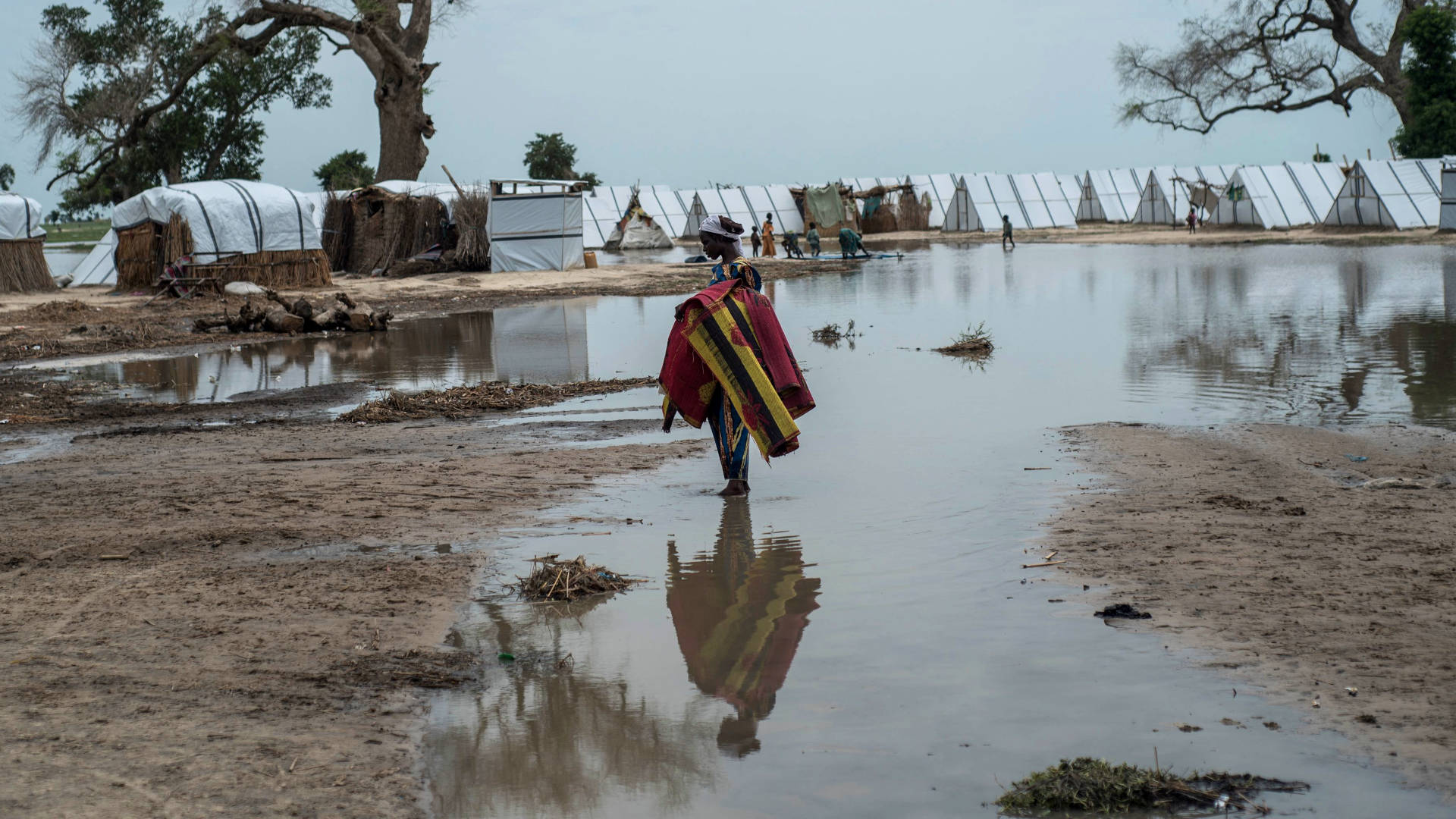 In July 2017, a woman stands in a pool of water created by heavy rainfall in an internally displaced persons camp in northeast Nigeria.