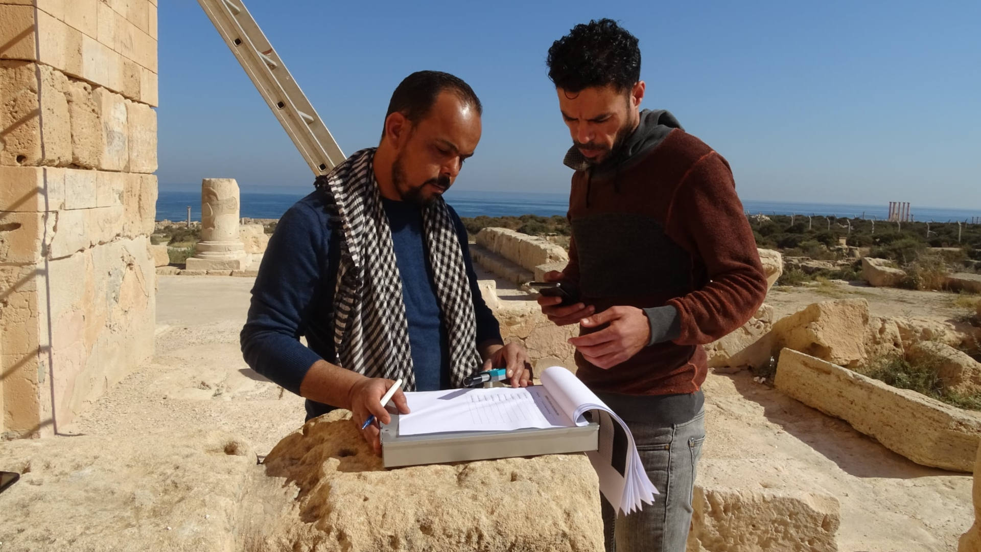 Mahmoud Hadia (left) and Ahmed Masoud (right) record bullet hole measurements at Sabratha, an ancient Roman theater that was damaged during fighting in 2017.