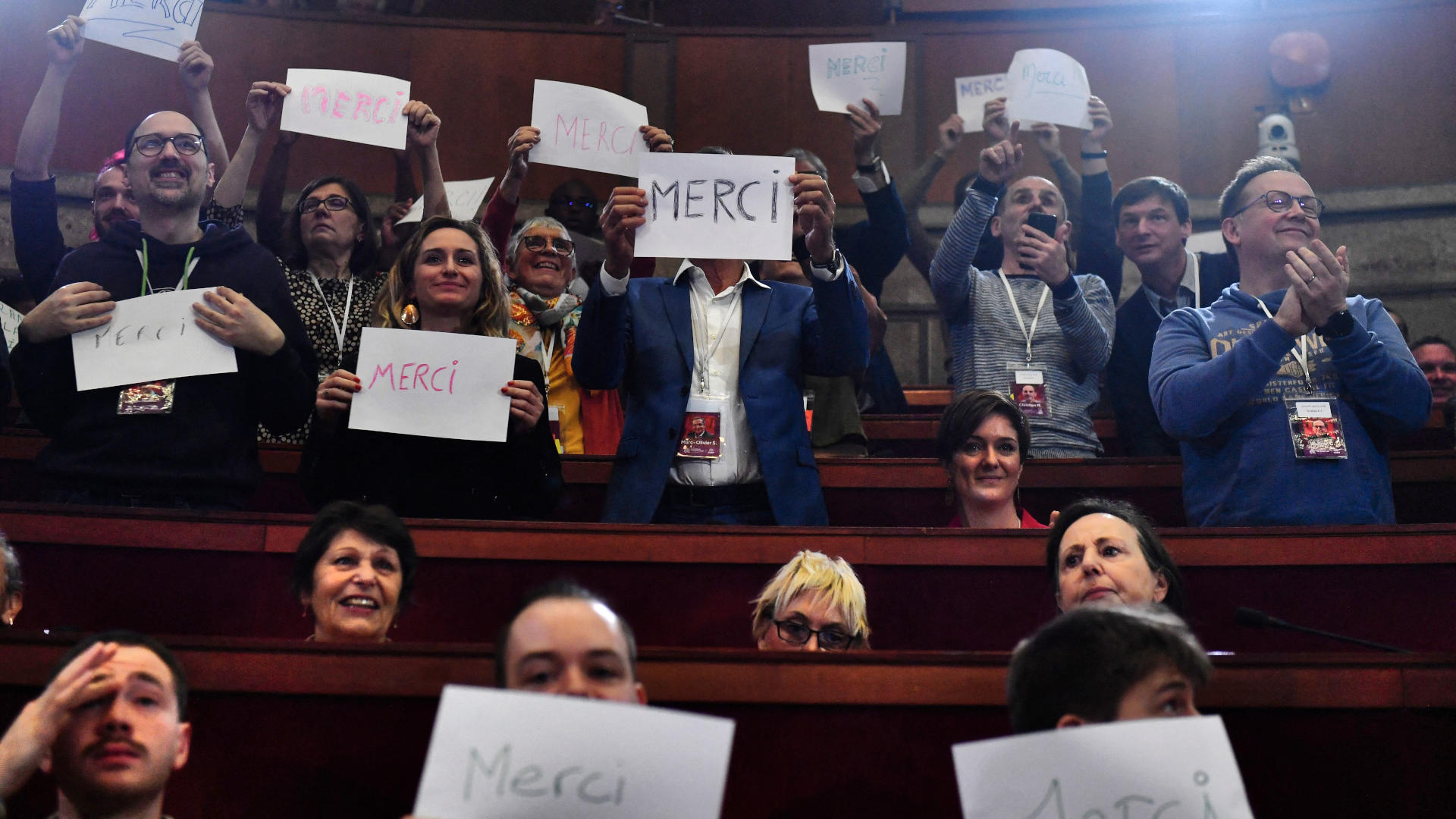 At the closing meeting of the Citizens' Assembly on the End of Life in Paris this April, attendees hold signs reading "Thank you" in French.
