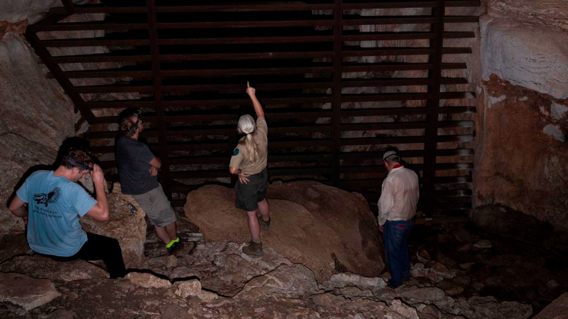 Debbie Hicks, Texas State Park Ranger, second from right, points toward the gate that blocks people from the depths of Gorman Cave during a visit to survey the bat population.