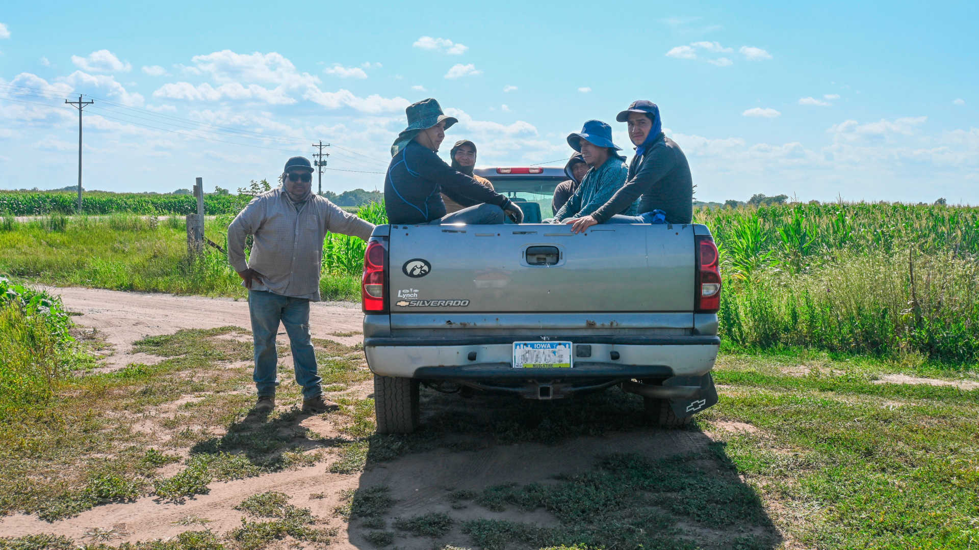 Juan Peña (seated at left) takes a break with other farmworkers in a field in southeastern Iowa on July 20, 2023. Their crew leader (standing) said summers have gotten hotter over the years.