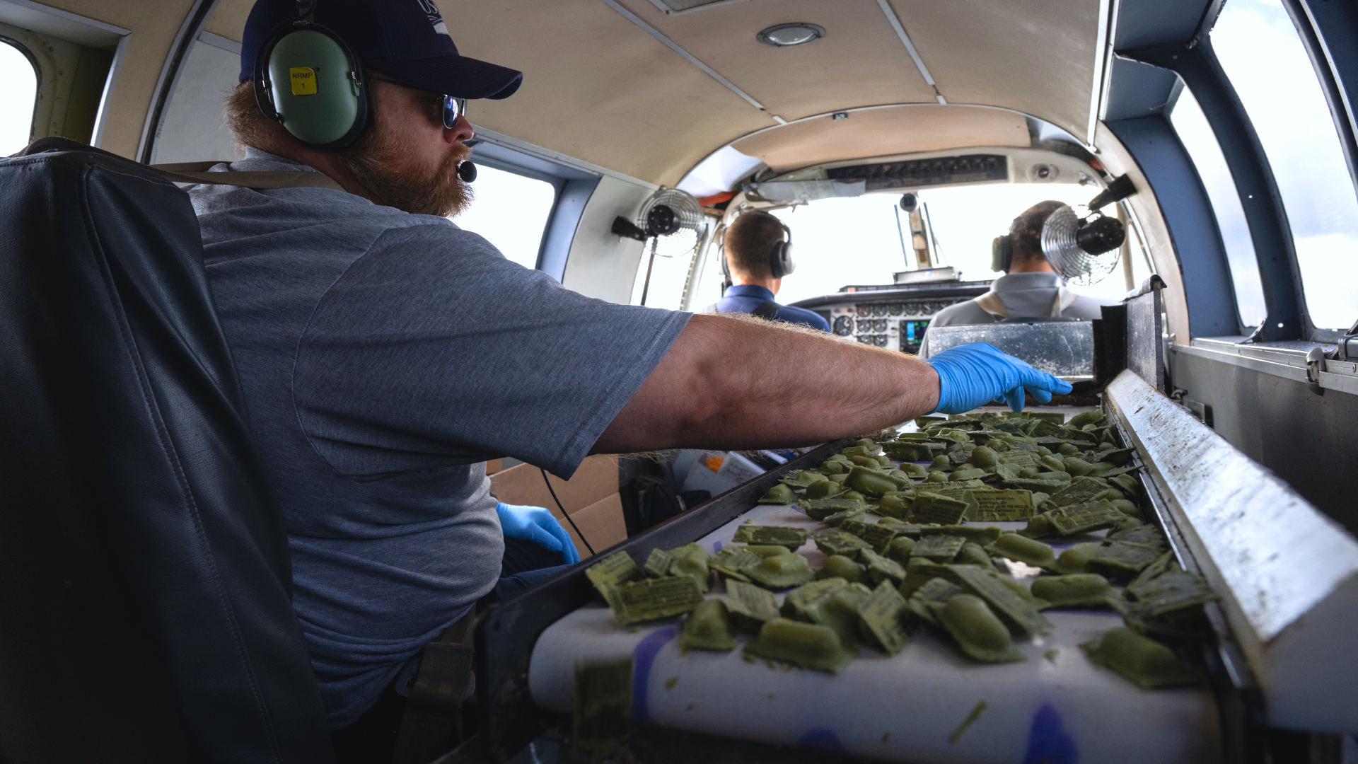 USDA wildlife specialist Brandon Hofer monitors the amount of ONRAB Oral Rabies Vaccine baits on a conveyor belt for air drop in West Virginia on August 26, 2023.