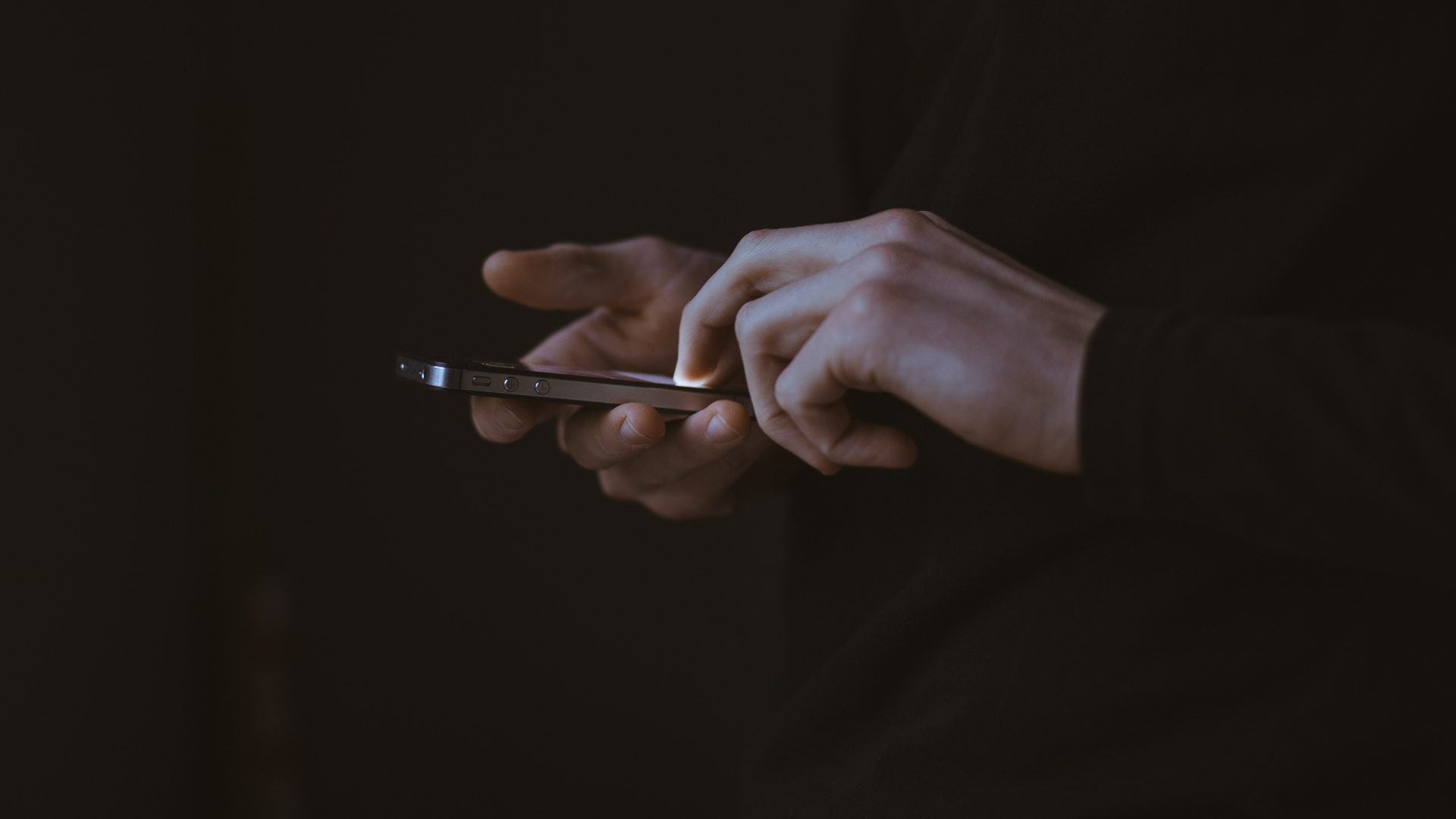 hands on a dark background holding a phone
