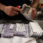 In a windowless hangar at New York's John F. Kennedy International Airport, dozens of law enforcement officers sift through packages sent through the U.S. Postal Service, looking for fentanyl. Here, one officer finds Oxycodone pills.