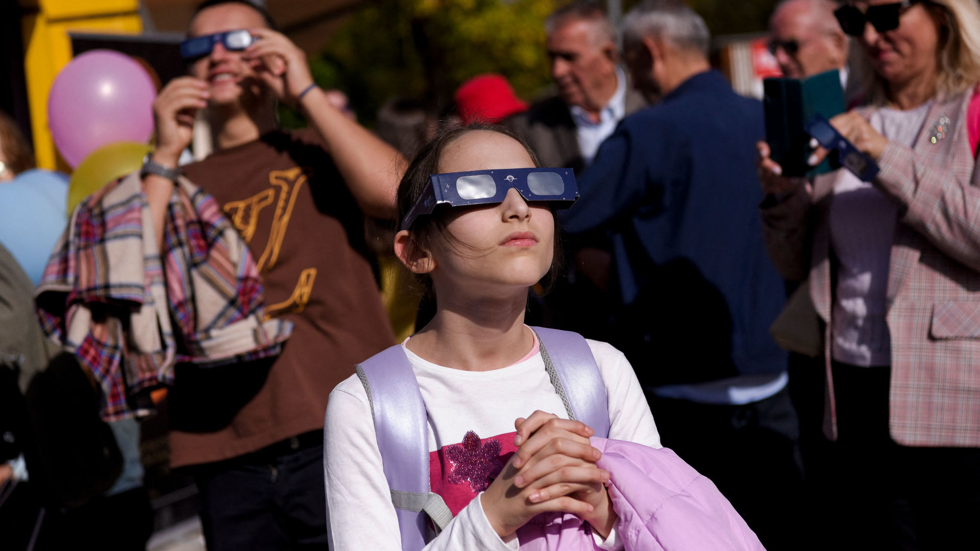 A girl uses protective glasses to watch a partial solar eclipse in Prishtina, Kosovo, on October 25, 2022. In recent years, astronomy enthusiasts have helped drive the development of science infrastructure in the young Balkan country.