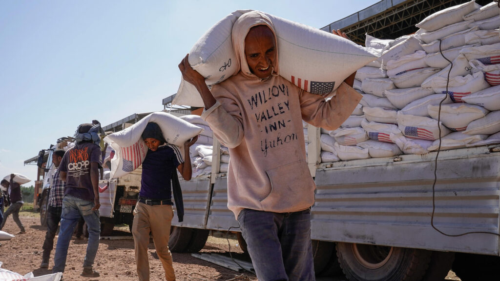 Volunteers at the Zanzalima Camp for Internally Displaced People unload wheat flour that was a part of an aid delivery from USAID on December 17, 2021 in Bahir Dar, Ethiopia.