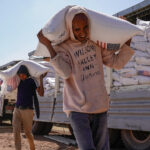Volunteers at the Zanzalima Camp for Internally Displaced People unload wheat flour that was a part of an aid delivery from USAID on December 17, 2021 in Bahir Dar, Ethiopia.