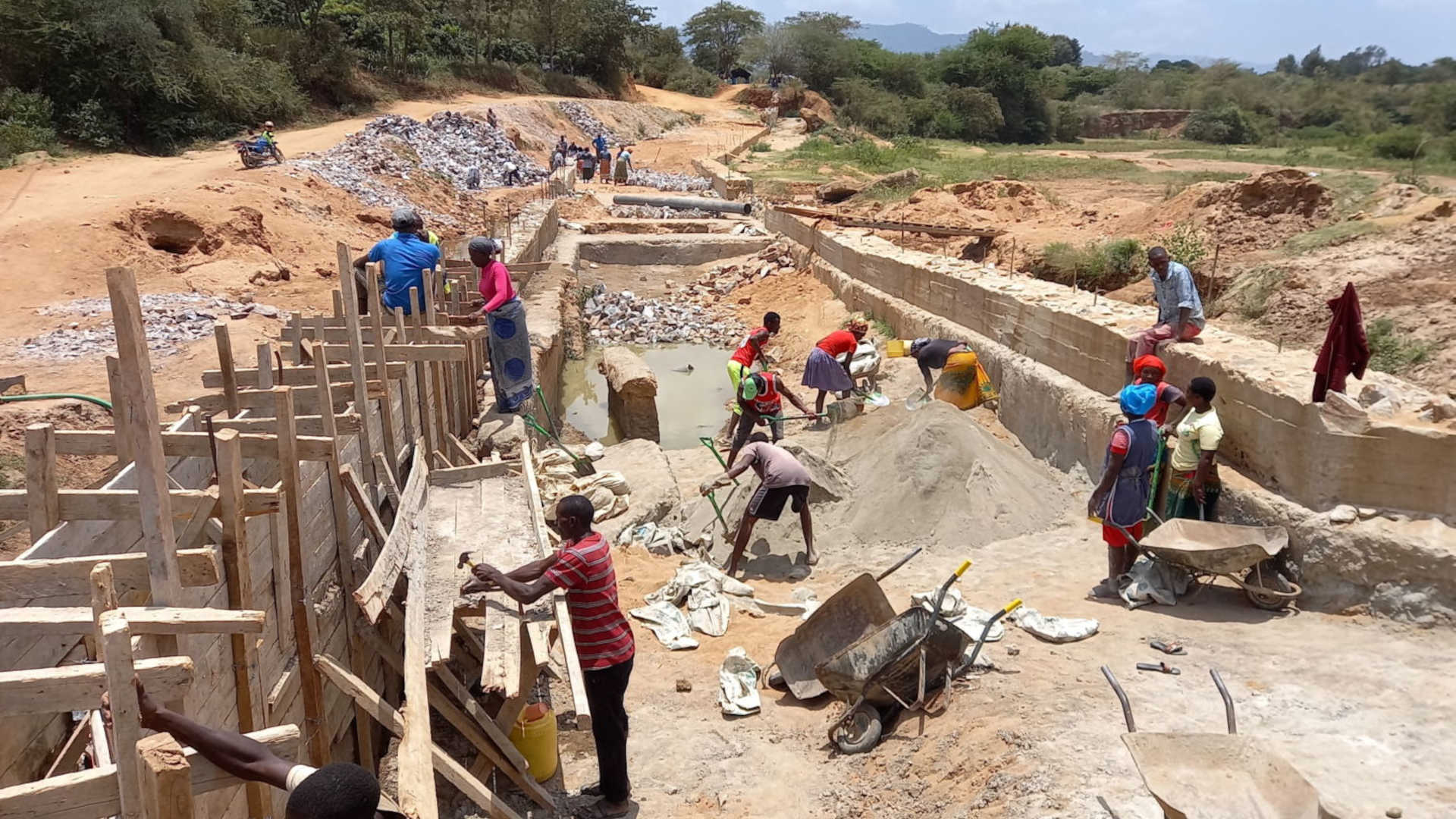 Villagers in Tawa, Kenya erect a concrete drift, a segment of road that doubles as a dam.