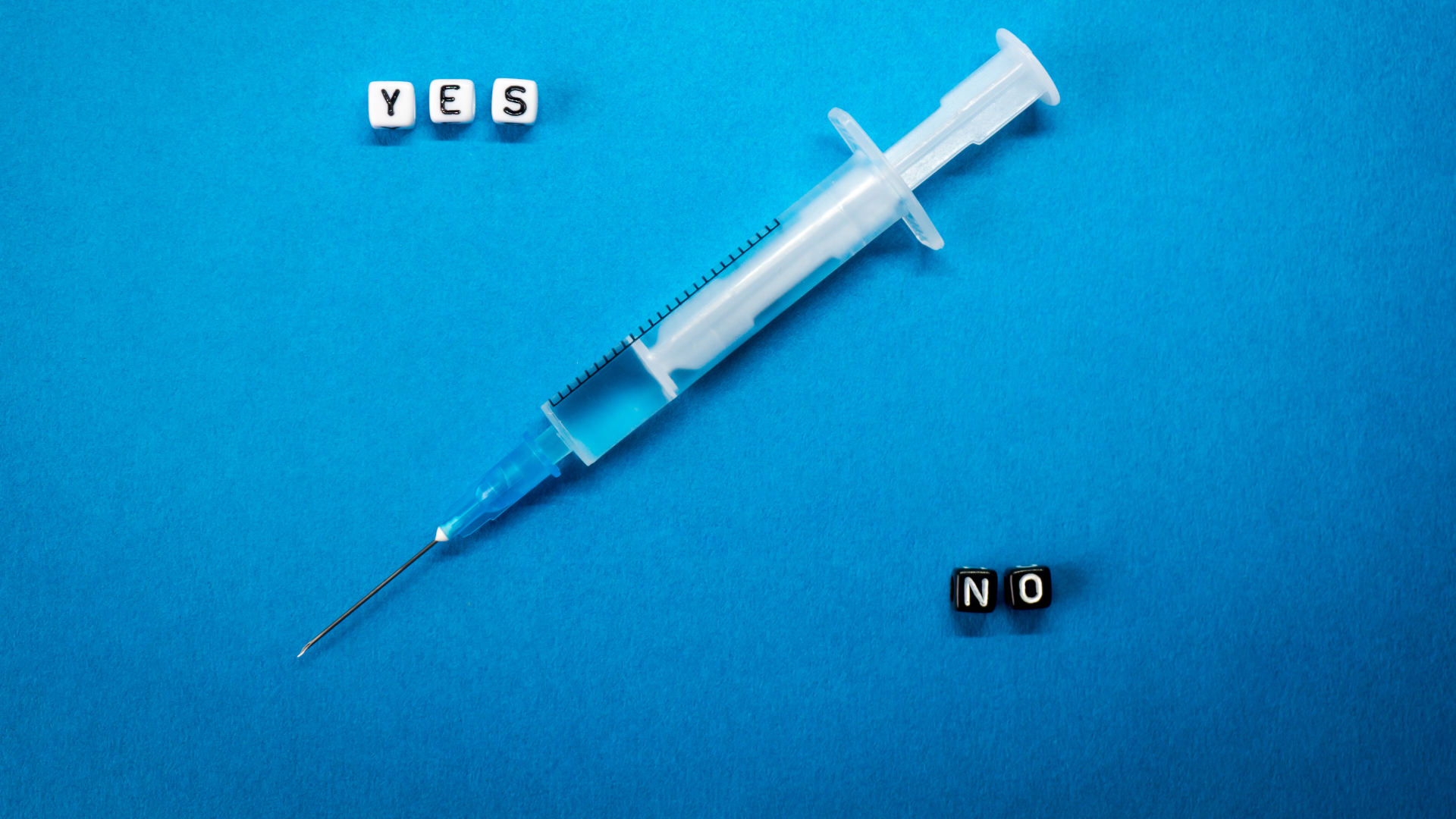 Yes No words made of square letters and a syringe on blue background.