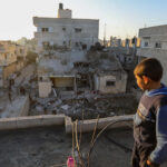 On February 21, 2024, a boy stands atop a damaged building following Israeli air strikes in Rafah, Gaza.