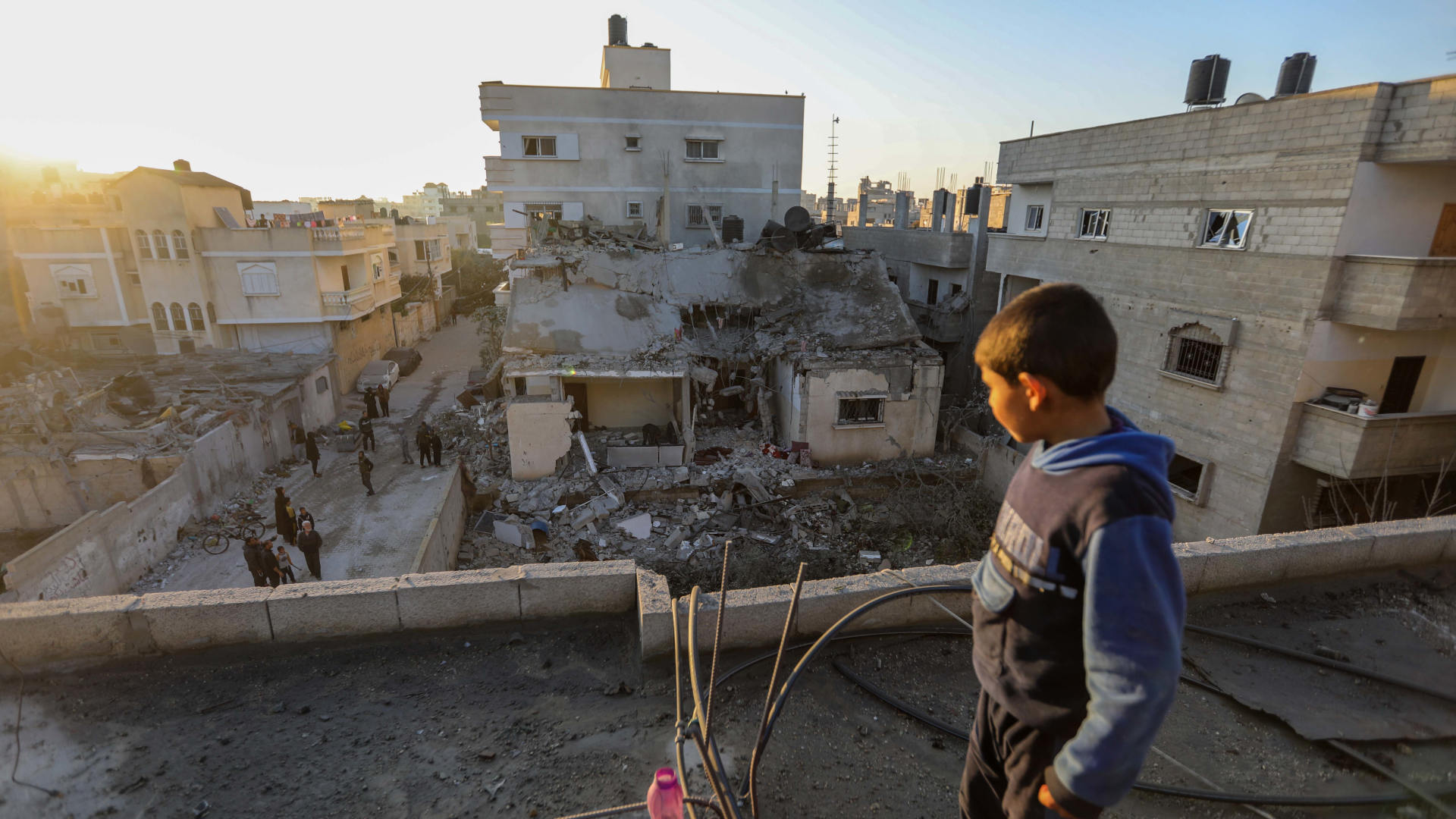 On February 21, 2024, a boy stands atop a damaged building following Israeli air strikes in Rafah, Gaza.
