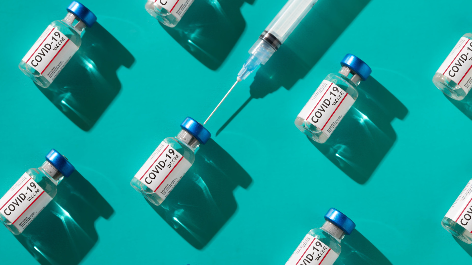 Covid 19 coronavirus vaccine vials with syringe repetition pattern with trendy lighting on teal background