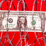 $1 US dollar bill inside coil of steel barbed wire, red background