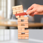 risk concept. Businessman in blue shirt holding wooden cube from wooden cube tower
