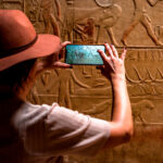 Personal perspective of woman photographing Egyptian hieroglyphics with smartphone at Kagemni Tomb, Saqqara, Egypt