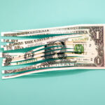 Conceptual image of a shredded one dollar bill with a colored background