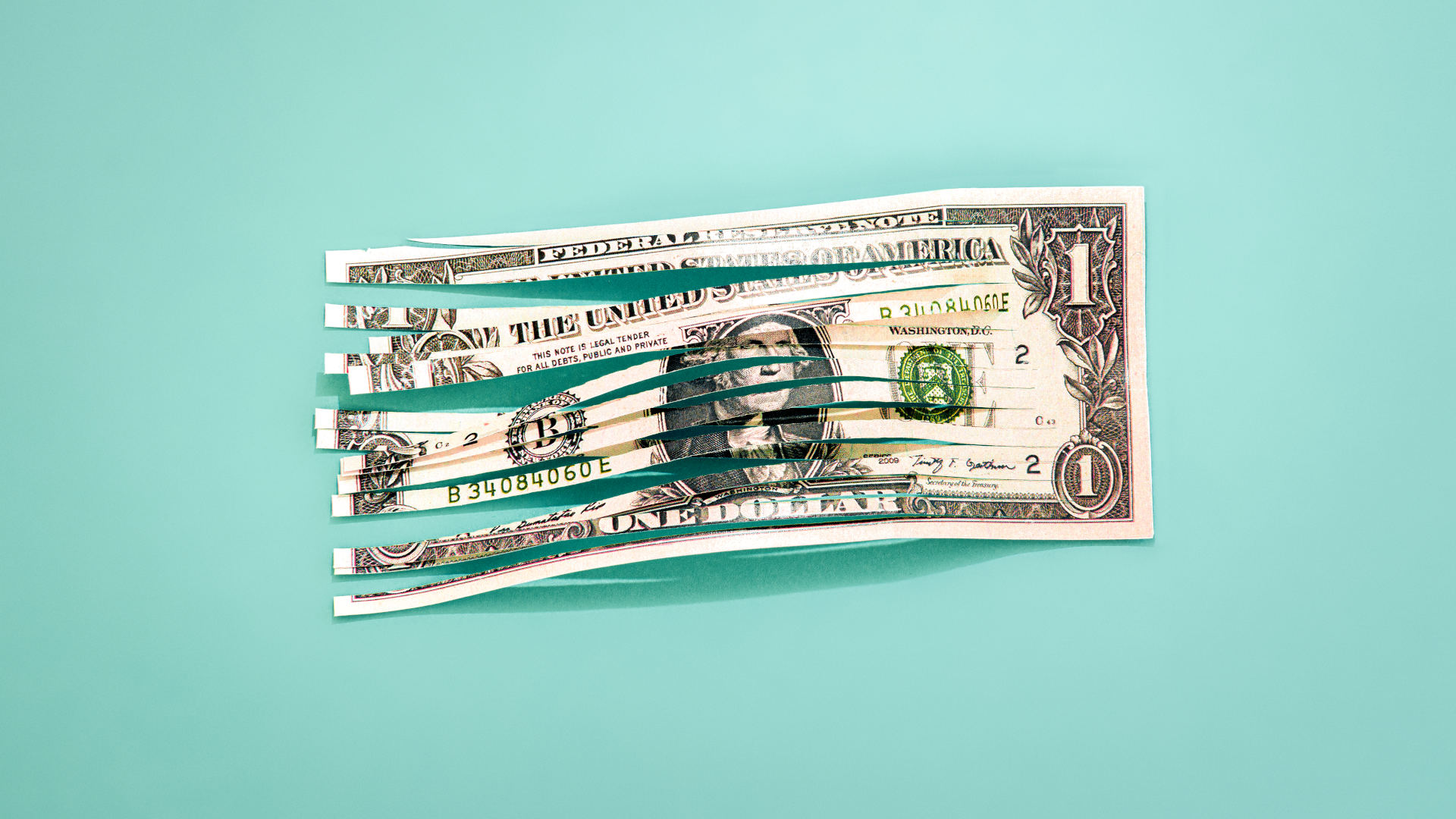 Conceptual image of a shredded one dollar bill with a colored background