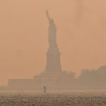 statue of liberty against a hazy orange sky