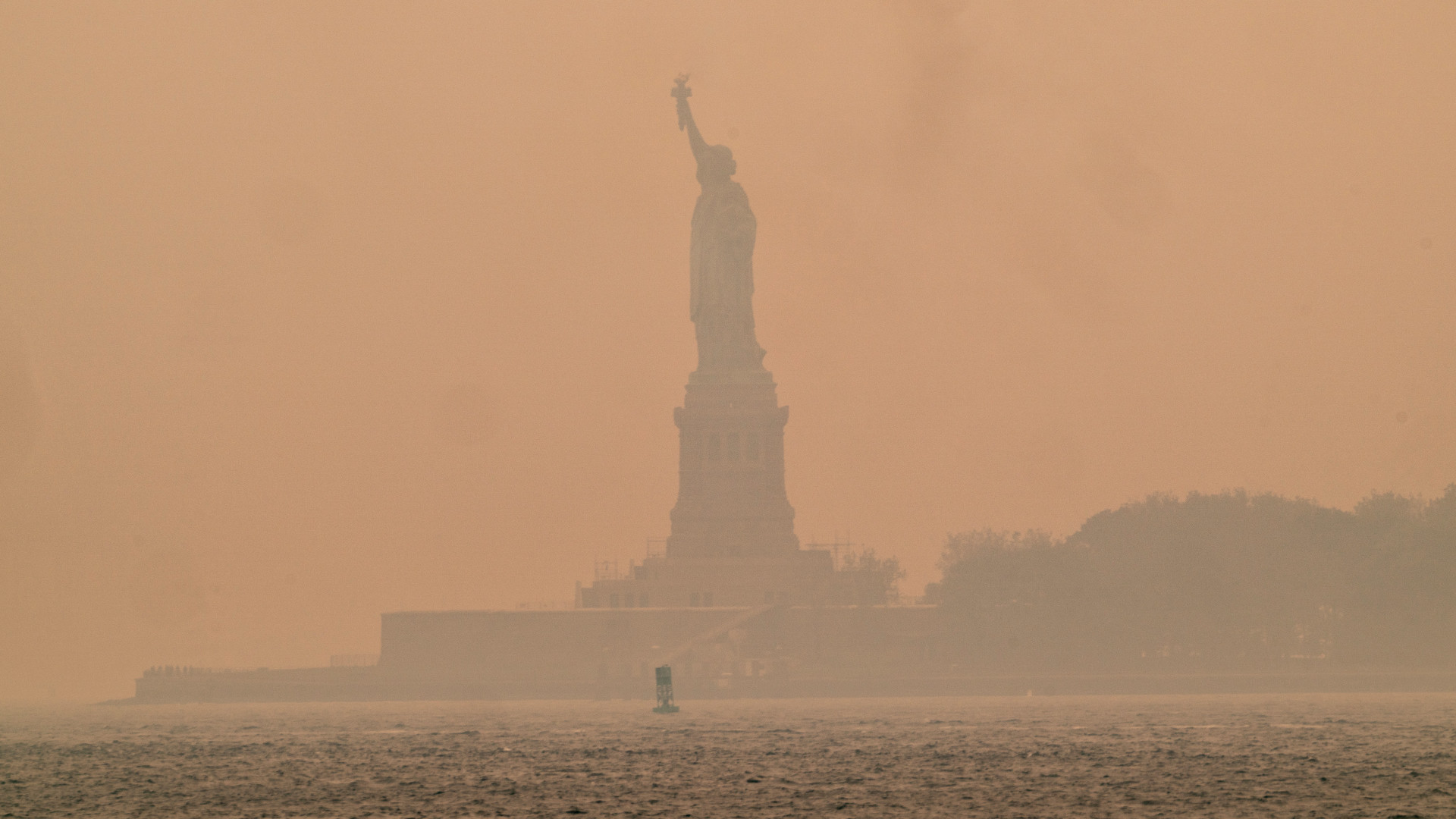 statue of liberty against a hazy orange sky