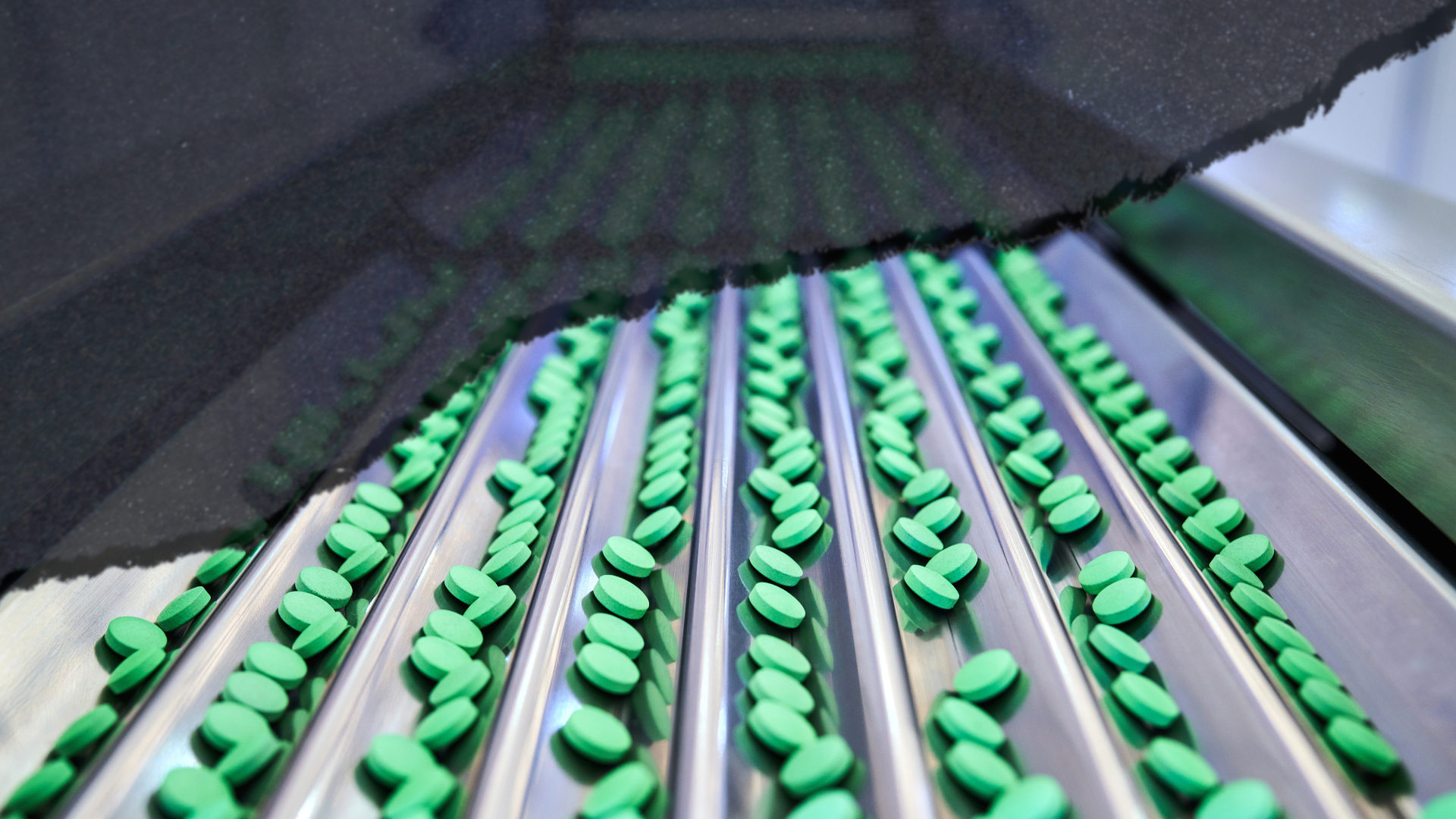 Front view of the green pill at conveyor belt in the pharmaceutical factory.